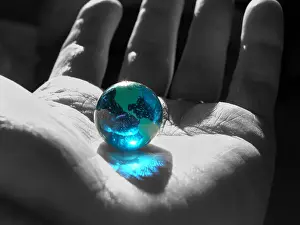 B&W hand with color earth marble