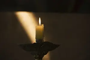 Candle Burning With Sun Ray On The Wall In The Background