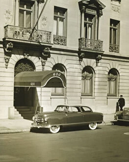 Car standing in front of hotel entrance, (B&W)