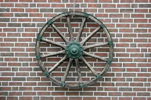 Hangs Prints: Cart wheel on a clinker brick facade in East Friesland, Lower Saxony, Germany, Europe