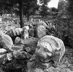 A carved lions head amongst the ruins of the bouleuterion or council chamber at Olympia