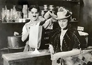 Prints of (Original Caption). Movie Still. Charlie Chaplin in Sunnyside': A First National Attraction. Chaplin behind counter of retail store waiting on female customer Master of Mime, Icon of Cinema: Chaplin in Prints: Charles Chaplin In Sunnyside