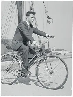 Charles Duval on His Invented Bicycle near Boat Dock