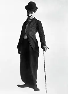 Prints of Full length shot of Charlie Chaplin in typical pose and attire--long-tailed coat, baggy trousers, bowler hat slightly cocked, bambu cane. Undated photograph Master of Mime, Icon of Cinema: Chaplin in Prints: Charlie Chaplin as the Little Tramp