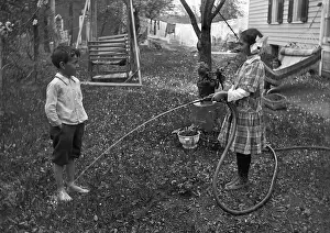 Splashing Prints: Children (6-7 years) playing with hose in garden