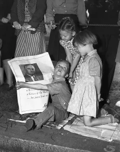 Mourner Prints: Children Gather Around a Newspaper