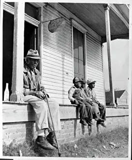 Children and Man Sit in Front of a General Store