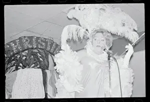 Christine Jorgensen in Frilly Costume and Singing at Microphone