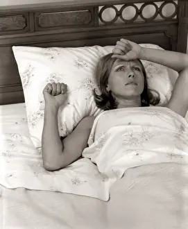 Lying Down Prints: Close-Up Woman Lying In Bed With Pained Expression Holding Hand To Forehead Indoor