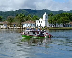 Images Dated 23rd October 2016: Colourful boat sailing with the pretty Brazilian town Paraty in the back ground