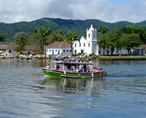 Port Town Of Paraty Prints: Colourful boat sailing with the pretty Brazilian town Paraty in the back ground