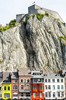 Colourful building fronts with steep cliff and medieval fortress on top