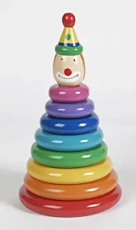 Medium Group Of Objects Prints: Colourful plastic rings stacked on pole with smiling clown head at the top, close up