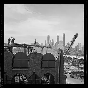Prints of BROOKLYN, NY - MARCH 1958: Constriction workers build a building with the Manhattan Skyline in the background in Brooklyn Heights, in March, 1958 in New York City, New York Portraits, Artworks, and Montages from a Visionary Photographer: Construction Workers in Brooklyn Heights in the 1950's
