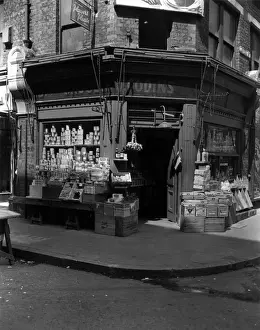 Store Window Prints: The Corner Shop; : A London grocers with goods on display outside
