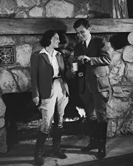Couple by fireplace wearing riding clothes (B&W)