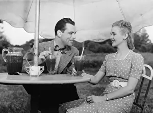 Couple having ice tea outdoors, (B&W)