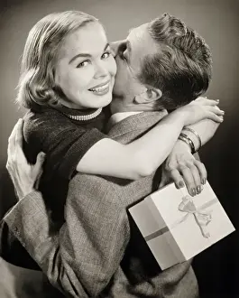 Couple hugging, woman holding gift, (B&W)