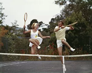 Images Dated 8th July 2016: Couple jumping on tennis court, smiling