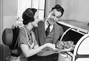 Mid Adult Couple Prints: Couple in kitchen, wife taking roast from oven, (B&W)