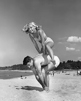 Couple playing leapfrog on beach