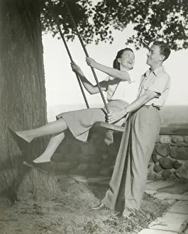 Couple playing on tree swing