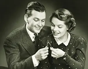 Mid Adult Couple Prints: Couple pulling wishbone in studio, (B&W), close-up, portrait
