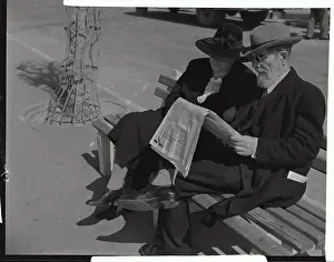 Couple Reading Newspaper Together on Bench