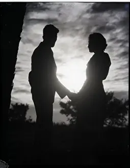 Couple Silhouetted In Sunset Holds Hands