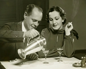 35 39 Years Collection: Couple sitting at table, man pouring drinks, (B&W)