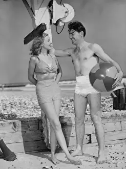Couple standing on beach, talking, (B&W)