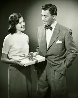 Ribbon Sewing Item Prints: Couple standing in studio, woman holding present, (B&W)
