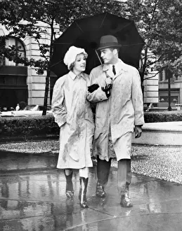 Couple w / umbrella walking in the rain