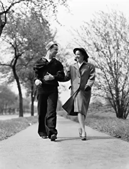 Romance Prints: Couple walking arm in arm outdoors, man wearing naval sailor uniform, woman wearing coat