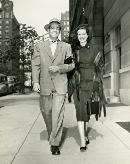 Arm In Arm Gallery: Couple walking arm in arm along sidewalk, portrait