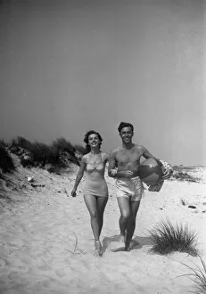 Sandy Beach Gallery: Couple walking on beach, man carrying ball, (B&W)