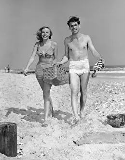 Couple walking with picnic basket on beach