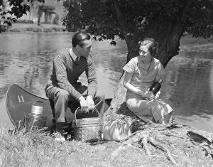 Couple Young Man Woman Smiling In Front Of Canoe With Picnic Basket Thermos Man Sweater