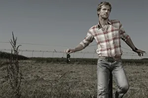 35 39 Years Gallery: Cowboy leaning against a wire fence
