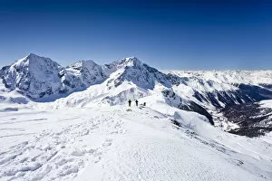 Cross-country skiers descending Hintere Schoentaufspitze Mountain, Solda, looking towards Koenigsspitze Mountain