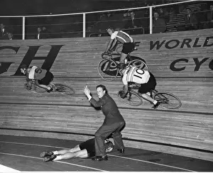 Prints of 16th June 1951: An official waves for assistance with a fallen cyclist as competitors race past on the banked circuit in a six day cycle race at Wembley A Photographic Legacy: Cycle Race