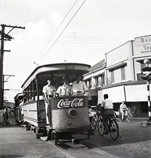 Siam Prints: Cyclists Peddle By Trolleys