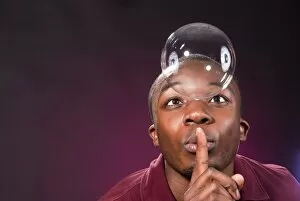 Dark-skinned young man with soap-bubble, making a gesture of silence