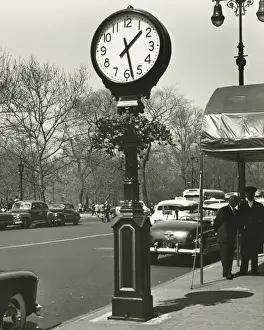 Awning Prints: Decorative street clock, two background people standing on street, (B&W)