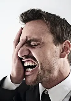 Necktie Prints: Desperate young man wearing a suit covering his face with his hand, screaming