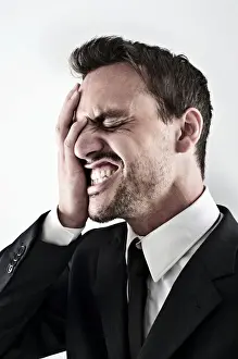 Annoyed Prints: Desperate young man wearing a suit covering his face with his hand, screaming