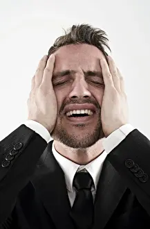 30 39 Years Prints: Desperate young man wearing a suit holding his hands to his face, worried