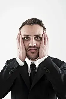 Annoyed Prints: Desperate young man wearing a suit holding his hands to his face, worried