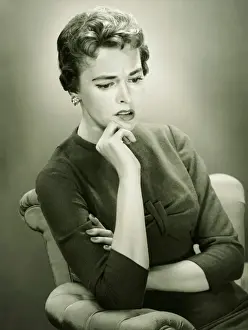 Introspection Prints: Distraught woman sitting in armchair in studio, (B&W), portrait