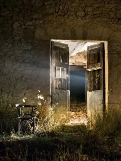 Aspirations Collection: Door of a house in ruins opened in the night with a beam of light